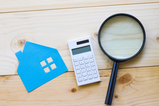 家の模型と虫眼鏡と電卓