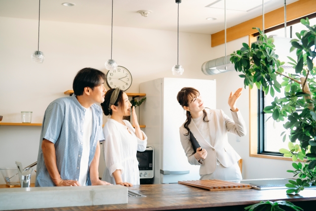 室内を案内しながら説明する女性と見学する夫婦のイメージ