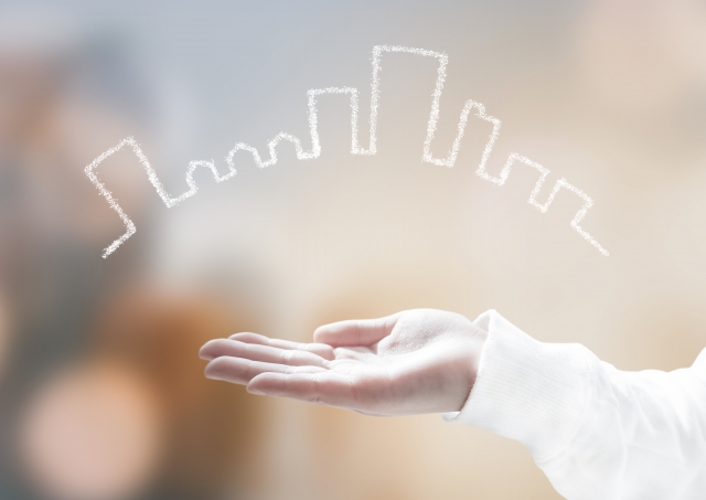 手のひらの上に建物の線画。住宅や街づくりを示すイメージ。