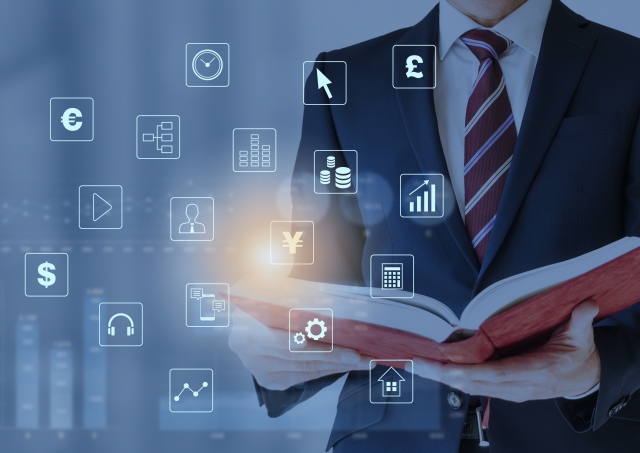 本を開くスーツ男性と金融アイコンのイメージ