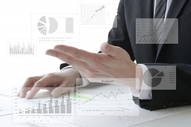 グラフ資料を示しながら説明するスーツ姿の男性