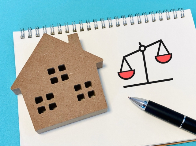 家の模型と天秤イラスト、ノートとペン
