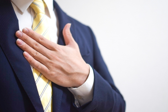 胸に手を当てるスーツ姿の男性