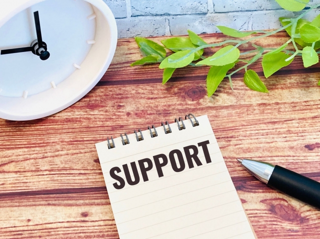 「SUPPORT」と書かれたメモ帳とデスク小物