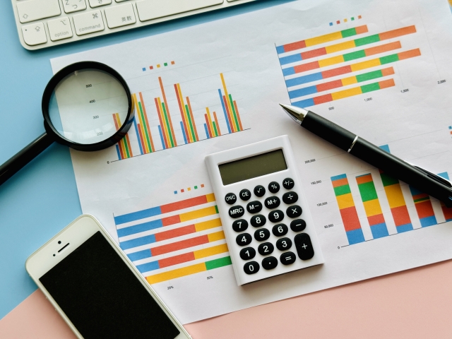 グラフ資料と電卓・虫眼鏡を並べた分析イメージ