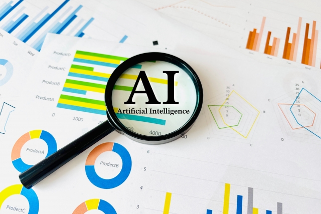 データグラフと虫眼鏡に映るAIの文字。