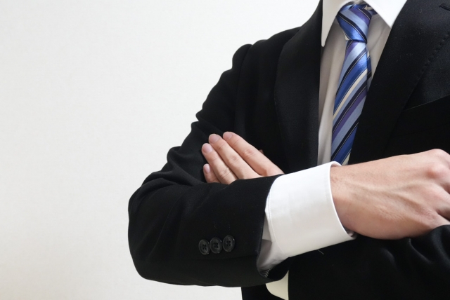 腕を組んだスーツ姿の男性。自信や信頼感を示すイメージ。