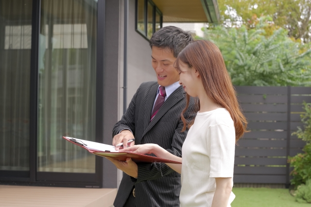 自宅前で書類を確認する男女の様子