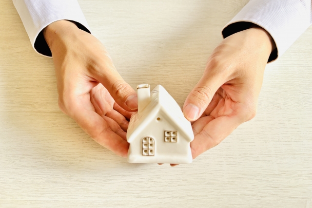 両手で家の模型を包み込む様子