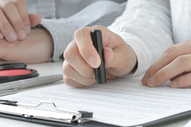 書類に押印する手元。契約手続きを示すイメージ。