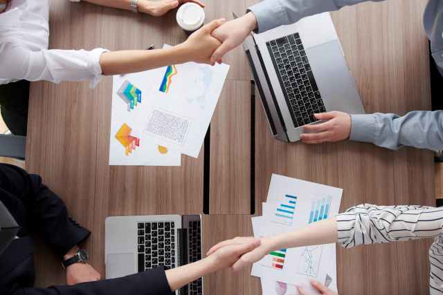 資料を挟んで握手するビジネスシーン